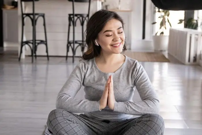 Mulher sentada em meditação numa sala com luz natural