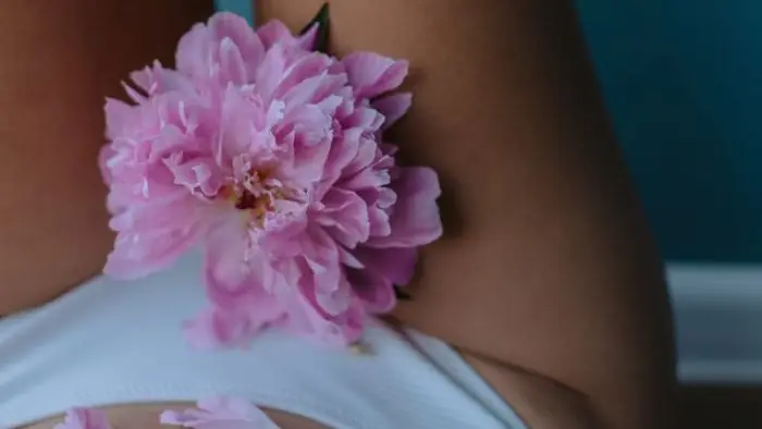 Peónia cor-de-rosa pousada sobre o corpo de uma mulher