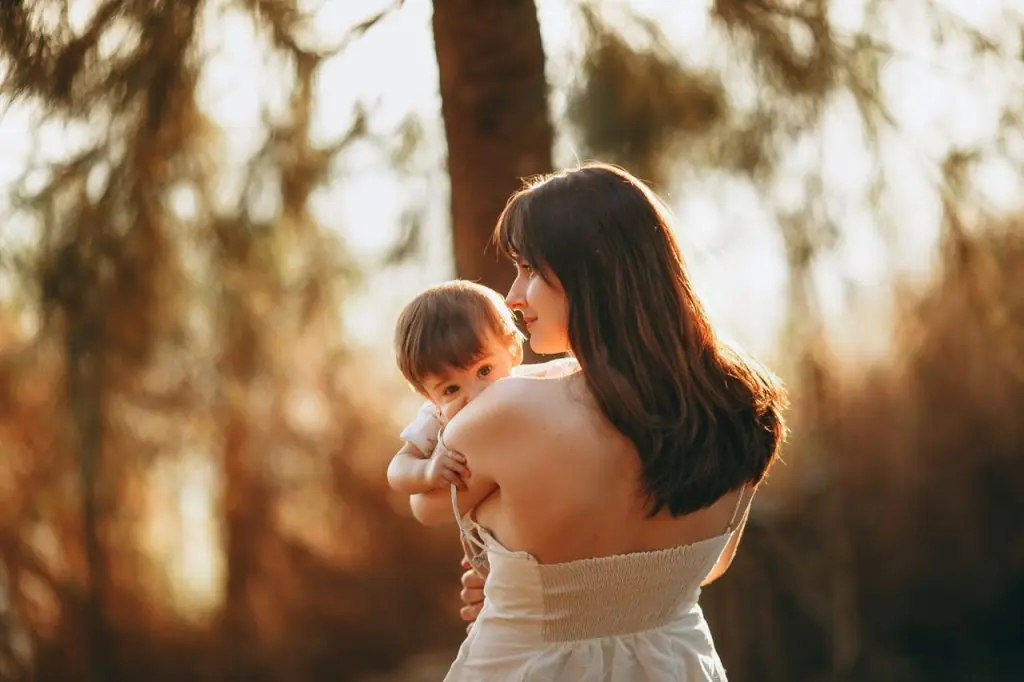 Mãe ao pôr do sol com o bebé ao colo